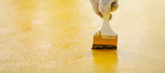 This image shows a man painting a floor using a paint brush.