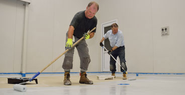 This image shows 2 men applying epoxy paint on a floor.