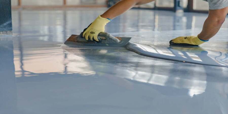 This image shows a man applying epoxy on a floor.